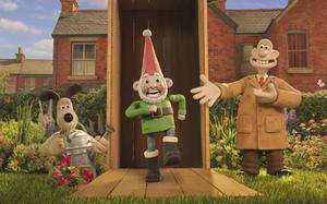 A stop-motion animation dog carrying a water can, a stop-motion animation gnome and a stop-motion animation human in front of a house in a garden.