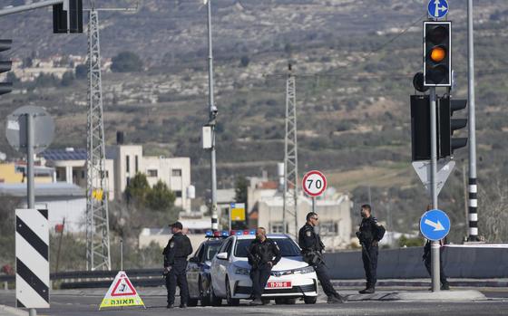 Several police officers are seen in front of a police car on an empty road.