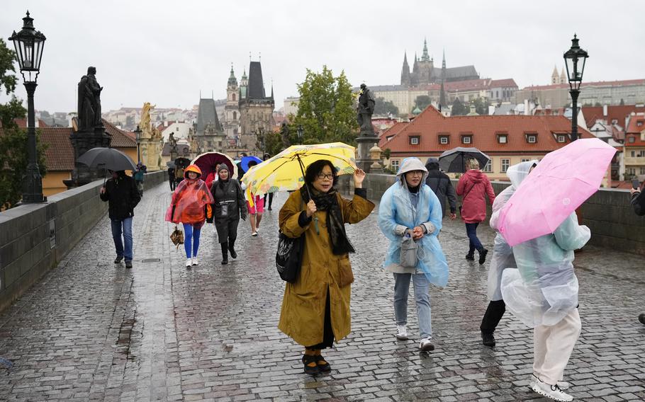 People with umbrellas against the rain as they cross the medieval Charles Bridge in Prague, Czech Republic, Friday, Sept. 13, 2024. 