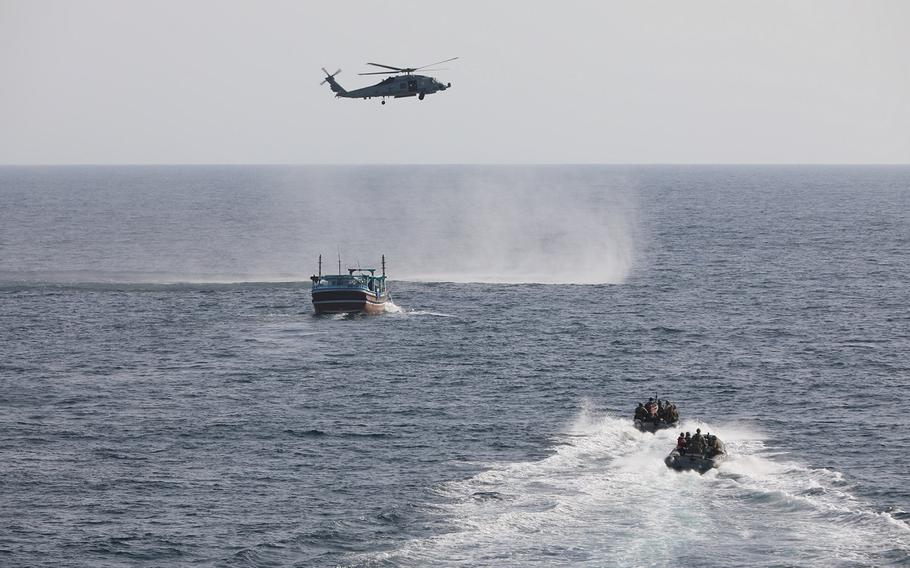 An interdiction team from the destroyer USS Delbert D. Black approaches a fishing vessel in the Gulf of Oman on Sept. 28, 2022, as an MH-60R Sea Hawk provides aerial support.