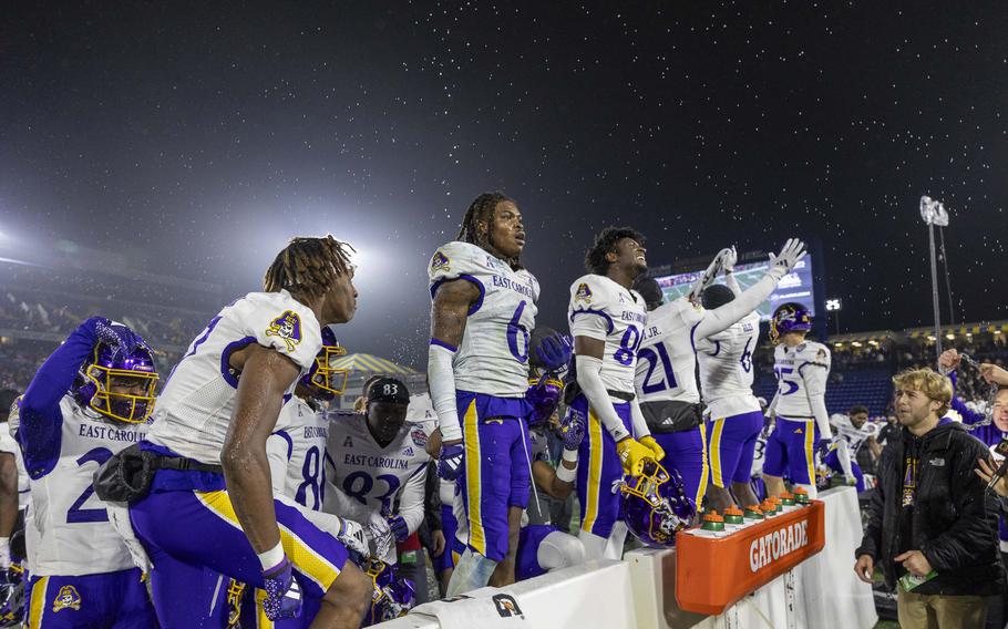 Football players stand and celebrate on a football field.