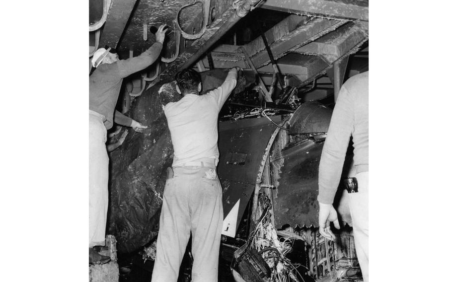  Crew members of the USS Oriskany examine the crushed remains of the Banshee jet