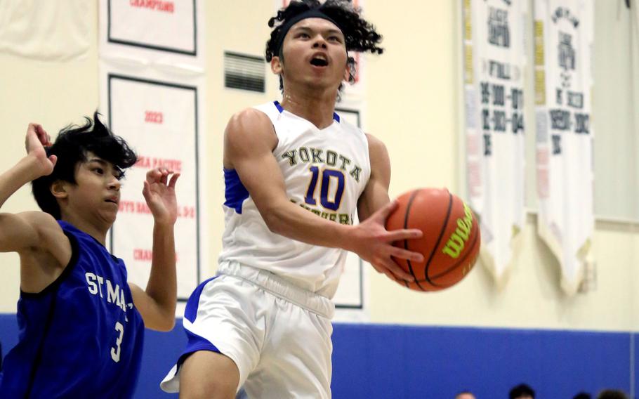 Yokota’s Royce Canta drives to the basket againsts St. Mary’s Towa Miyoshi during Thursday’s Kanto Plain boys basketball game. The Titans won 67-63 in a matchup of last year’s Far East Divisions I and II tournament champions.