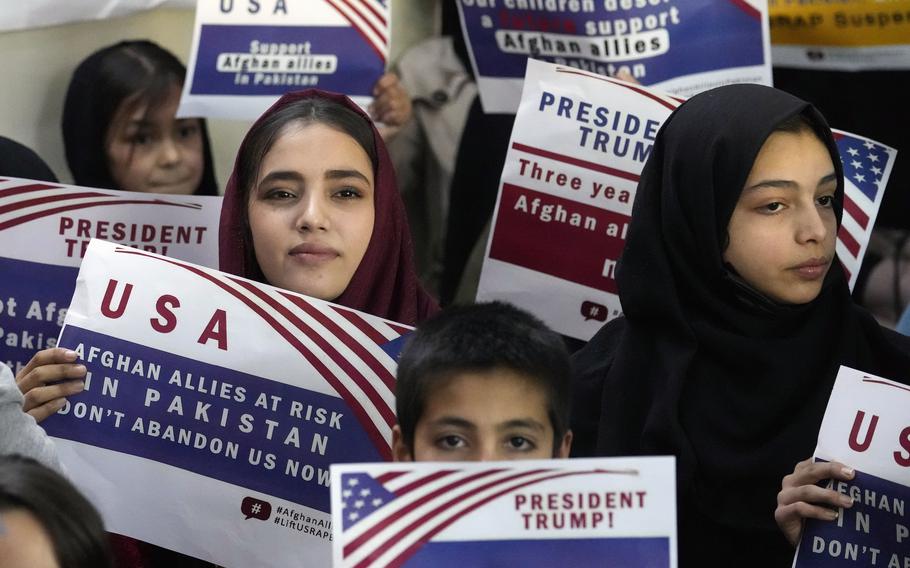 Afghan refugees hold placards during a meeting