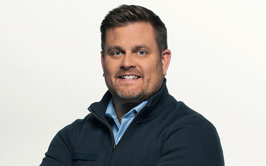 A caucasian man with blue eyes smiles in a professional headshot-style photo.