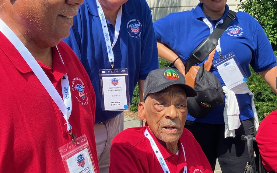 Calvin Kemp, a 101-year-old Navy veteran, is seated next to honor flight chaperones at Arlington National Cemetery prior to the start of ceremonies at the Tomb of the Unknown Soldier.