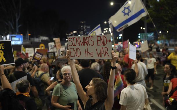 A demonstrator holds a sign about the killing of Hamas leader Yahya Sinwar during a protest calling for a cease-fire deal and the immediate release of hostages held by Hamas on Thursday, Oct. 17, 2024, in Tel Aviv, Israel. (AP Photo/Ariel Schalit)