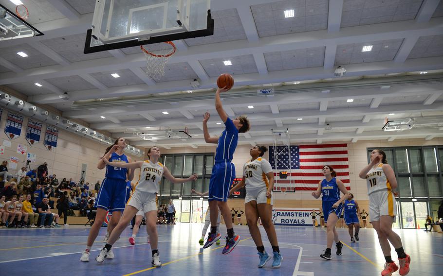 Wiesbaden’s McKinley Viers jumps for a layup as Stuttgart defenders Ella Kirk, left and Icsiss Perez look to grab a rebound at the DODEA European Division I girls basketball championships Feb. 16, 2023, at Ramstein Air Base, Germany. Wiesbaden beat Stuttgart 50-15.