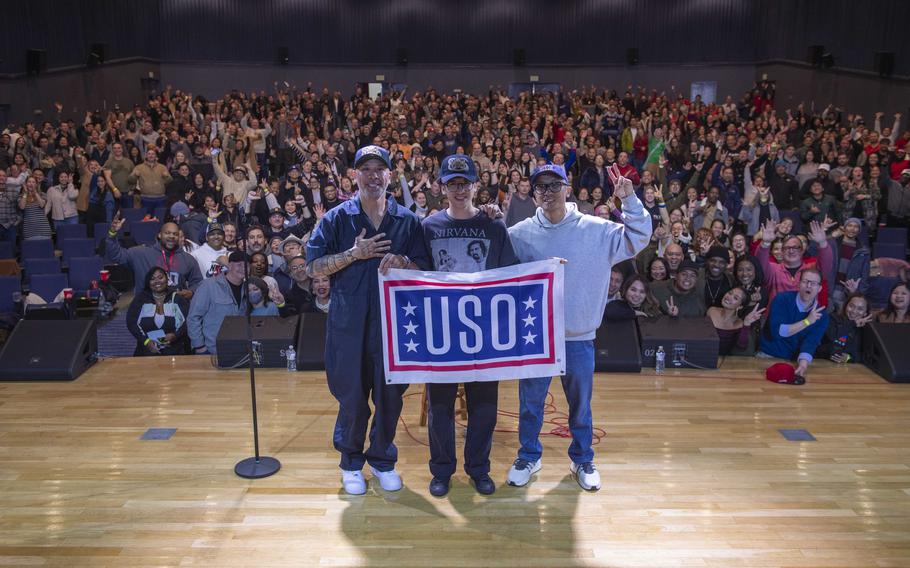 Jo Koy poses for a picture with the USO flag and a crowd of people