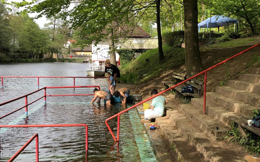 Parkgoers dip their feet in the lake and look at tadpoles at Bärenloch in Kindsbach, Germany, on May 1, 2024.