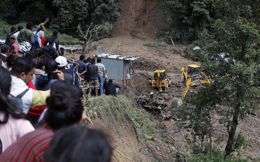 Rescuers search for victims trapped under a landslide caused by flooding in Nepal.