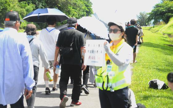 A volunteer holds up a sign directing mock evacuees during an exercise at Kadena Air Base, Okinawa, Sept. 7, 2024.