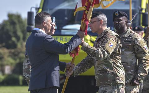 Col. David Mayfield passes the unit colors to Installation Management Command-Europe director Tommy Mize, as Mayfield relinquishes command of U.S. Army Garrison Wiesbaden on June 26, 2024, in Wiesbaden, Germany.