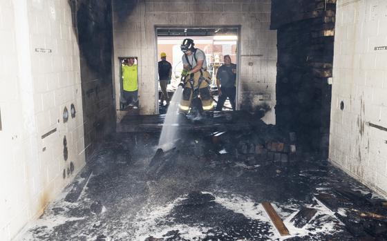 Firefighter Dorian Poling, 788th Civil Engineer Squadron Fire Department, hoses down debris July 19, 2024, from a fire at Building 18, Area B, Wright-Patterson Air Force Base, Ohio. The fire had started the night before but the construction of steel plates over wood timbers prevented the firefighters from completely extinguishing the embers. (U.S. Air Force photo by R.J. Oriez)