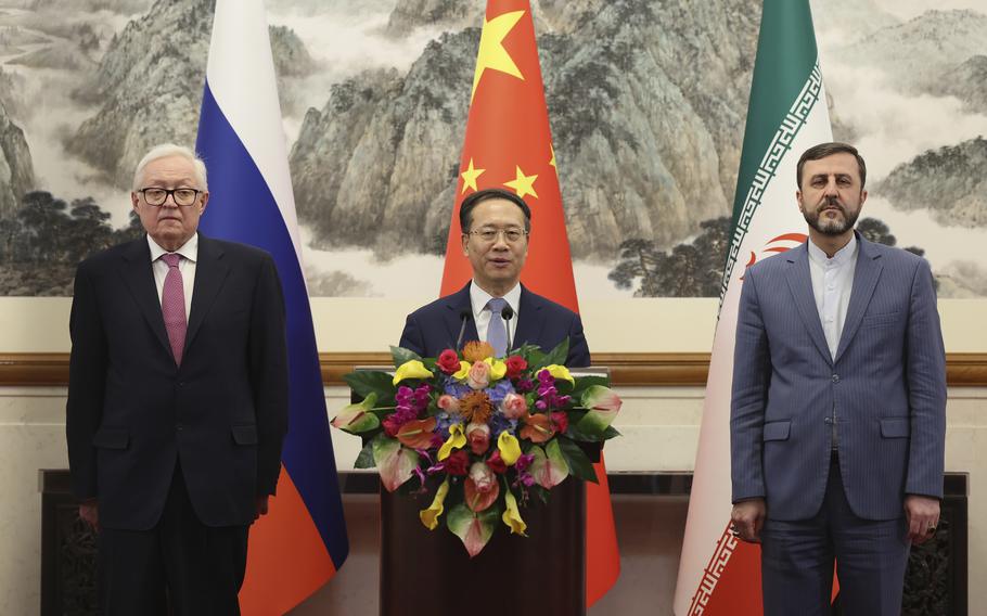 Foreign ministers representing Russia, China and Iran stand for a photo before their respective flags.