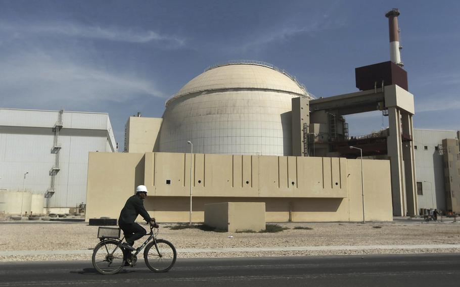 A worker rides a bicycle in front of a nuclear power plant.