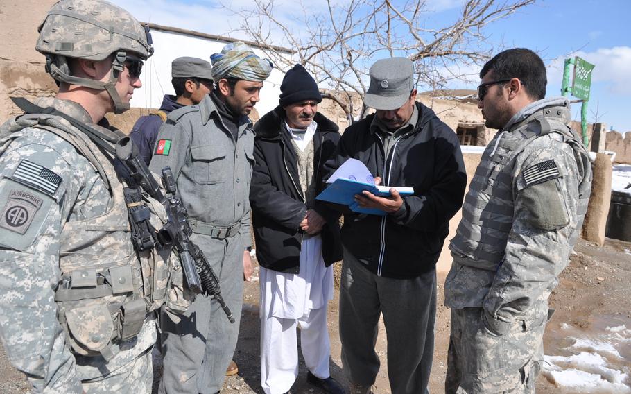 U.S. Army Capt. Dennis Williams, left, Troop A commander of the 4th Squadron, 73rd Cavalry Regiment, 82nd Airborne Division, looks on with Afghan National Police colleagues as Police Capt. Abdul Zaher, second from right, reviews the log at the police substation they were visiting on Feb. 8, 2010. The U.S. and Afghan forces went on a joint patrol to visit some police checkpoints in the Pashtun Zarghun district of Herat province.