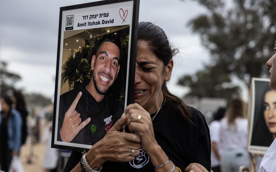 A woman sobs while holding up a picture of a relative.