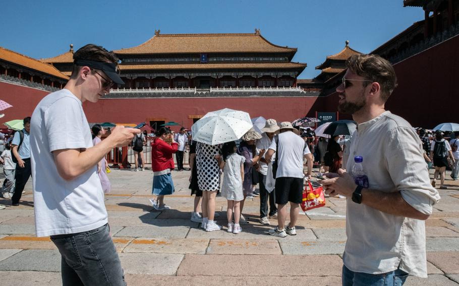 Two German tourists try to get tickets online before entering the Palace Museum at the Forbidden City.