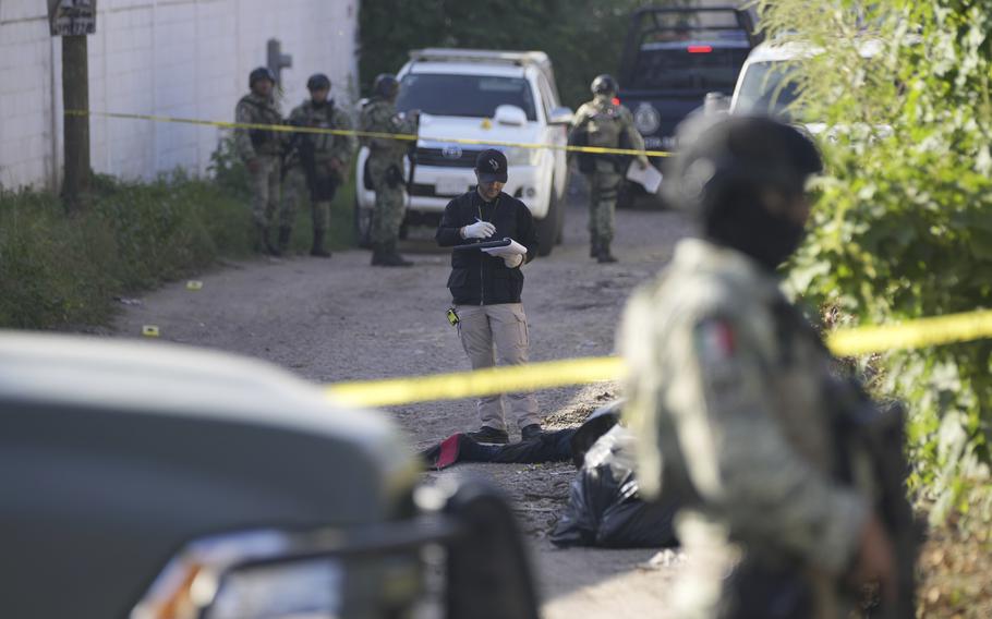 Forensic investigators work at the site of a body lying in the street