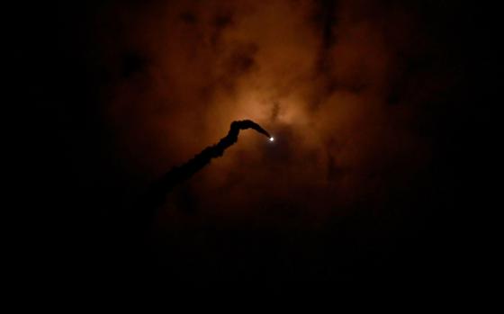 A dark sky with barely visible clouds and a trail of smoke following from a white pinpoint.