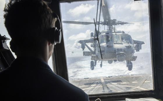 Lt. j.g. Austin Morretta watches from the tower as an MH-60S Sea Hawk helicopter lands on the flight deck of the Arleigh Burke-class guided-missile destroyer USS Spruance, part of the Abraham Lincoln Carrier Strike Group that is sailing toward the Middle East.