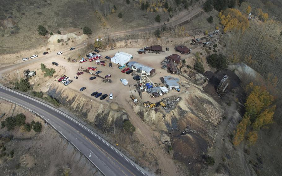 Overhead view of a dirt parking lot with emergency personnel outside the entrance to a mine.