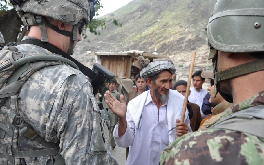 U.S and Afghan soldiers talk to a man at the Kandagal bazaar on July 20, 2010. The village is just across the Pech River from Combat Outpost Michigan.