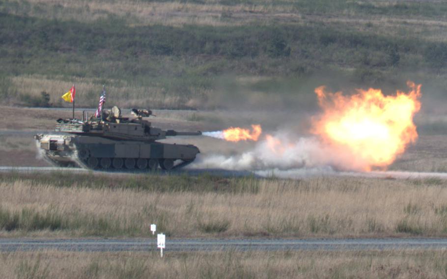 An M1A2 Abrams tank fires a round at a target.