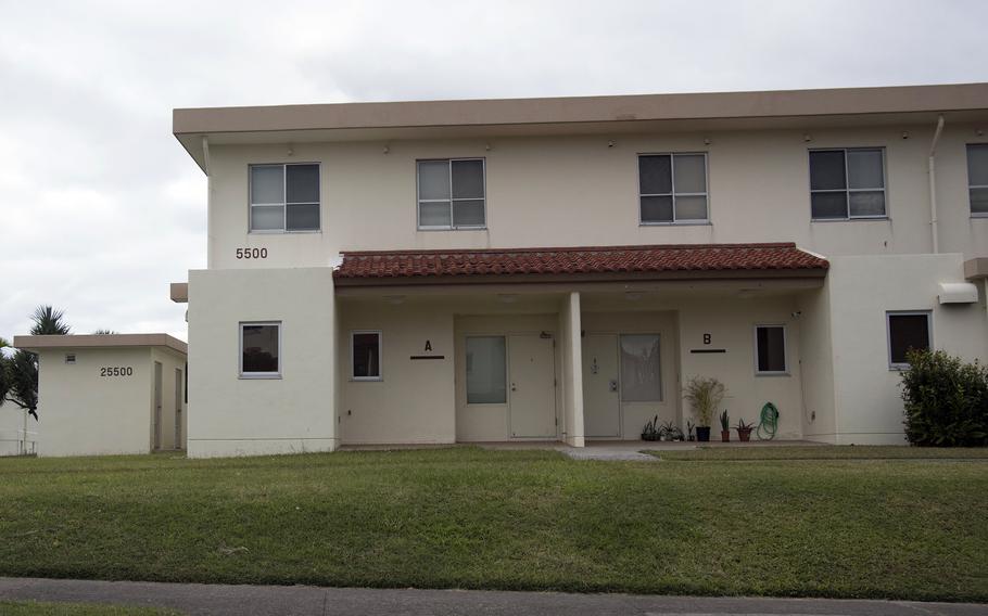 An exterior view of a military housing duplex with grass and a sidewalk in front.