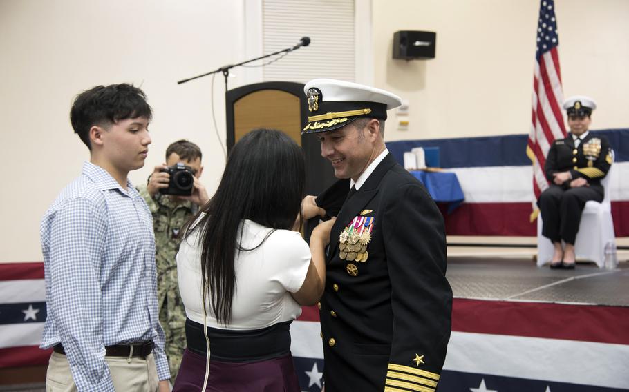 Capt. Joseph Parsons, head of the Navy's support activities on Okinawa, is pinned with the command ashore insignia by his wife, Rosa Parsons, alongside their son, also named Joseph Parsons, at Camp Shields, Okinawa, Dec. 12, 2024. 