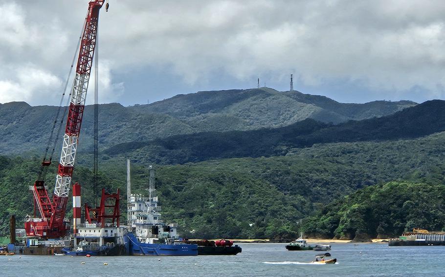 A crane floats in Oura Bay at the site of a runway construction project.