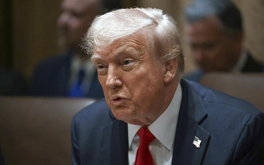 Donald Trump wears a blue suit, red tie and an American flag on his lapel as he speaks at a cabinet meeting.