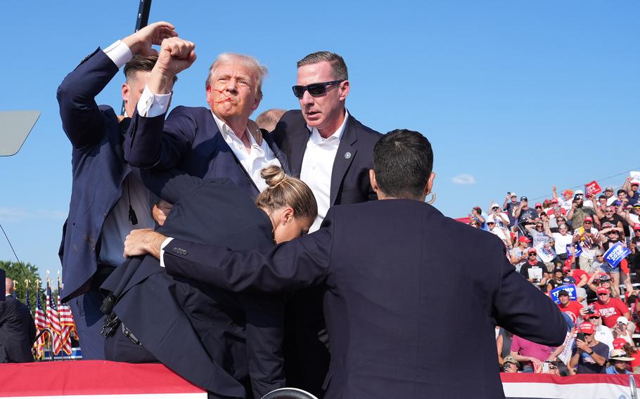 Former president Donald Trump raises his arm with blood on his face during a campaign rally on Saturday in Butler, Pa. Trump ducked and was taken offstage after shots were fired. 