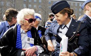 An elderly woman wearing sunglasses talks to a younger woman in a blue Air Force dress uniform.