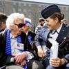 An elderly woman wearing sunglasses talks to a younger woman in a blue Air Force dress uniform.