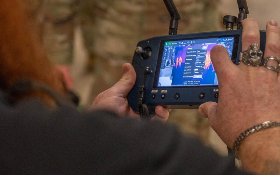 A civilian uses a finger on a touchscreen to control a drone.