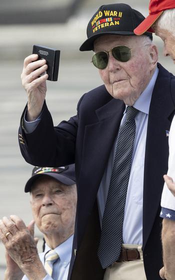 Veteran Jeffrey Donahue holds up a Greatest Generation coin during the 20th anniversary celebration of the National World War II Memorial in Washington, May 25, 2024.