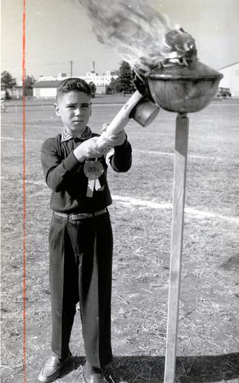 Torch bearer Tom Mulky lights the flame at the Junior Olympic Games. Seven sixth grade classes from the Tachikawa Air Base, Japan, Dependent Elementary School got together at the Tachikawa West Track Oct. 22, 1960, for their own version of the athletic classic. 