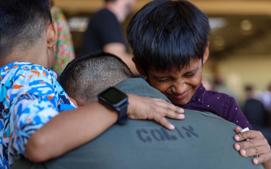 Marine embraces his children