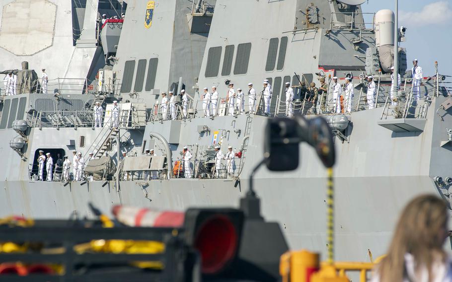 Sailors in white uniforms man the rails of USS Preble.