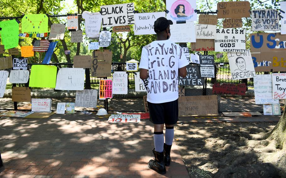 Latif Schofield looks at the protest signs and artwork on the fence surrounding the White House on June 7, 2020. 
