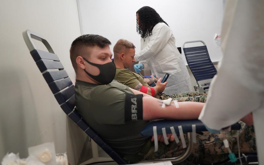 Marine sitting in a chair with his arm extended and bandaged after giving blood.