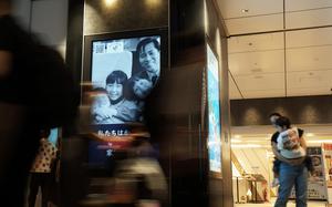 Tokyo Station commuters dart past video ads featuring the family of North Korean abductee Megumi Yokota, Aug. 21, 2024.