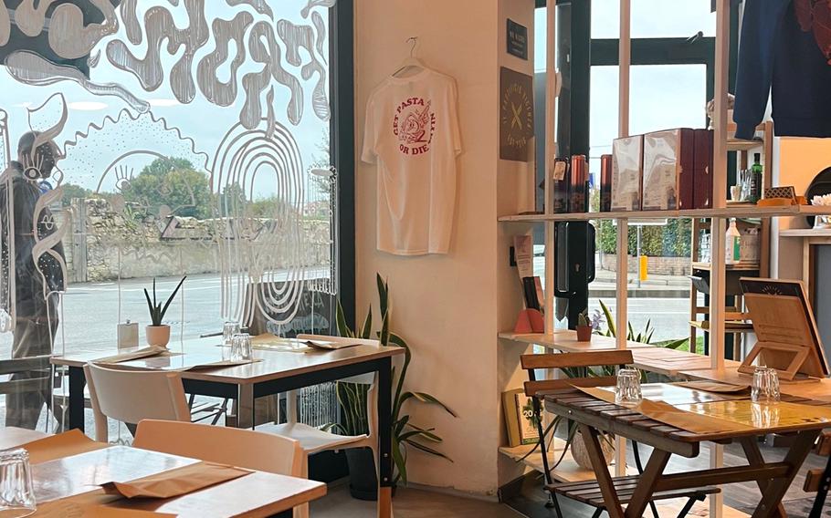 Wooden tables, a wooden wall and a decorated window wall show inside the restaurant.