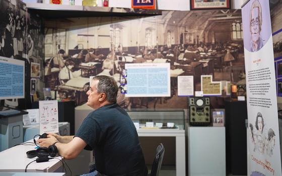 Adrian Paige-Mitchell, a worker at the Center for Computing History in Cambridge, England, shows as part of a tour on Aug. 31, 2024, what an office in the 1990s looked like. The museum seeks to present different periods of computer technology history using innovative means such as virtual reality. 

