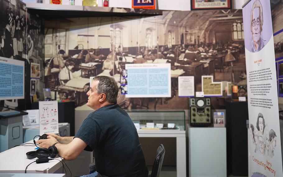 Adrian Paige-Mitchell, a worker at the Center for Computing History in Cambridge, England, shows as part of a tour on Aug. 31, 2024, what an office in the 1990s looked like. The museum seeks to present different periods of computer technology history using innovative means such as virtual reality. 