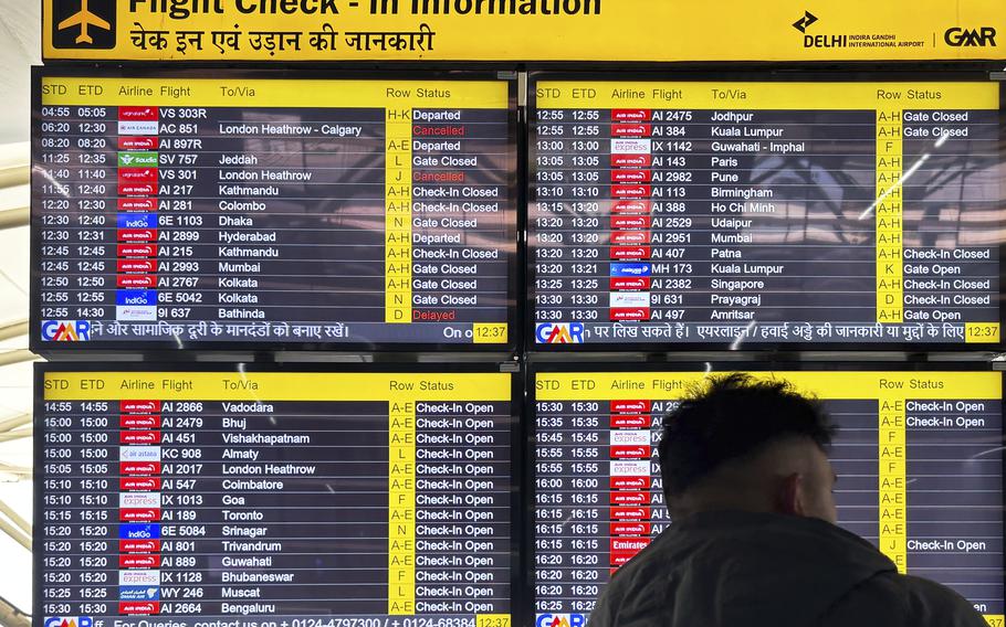 Dozens of flights are listed on screens below a sign reading “Flight Check-In Information.”