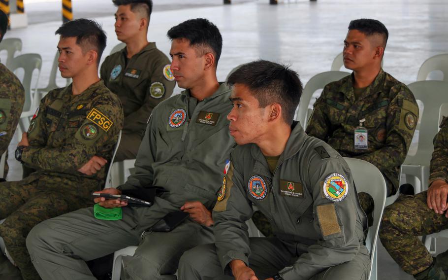 U.S. and Philippine soldiers sit in chairs and listen to air-mission planning.