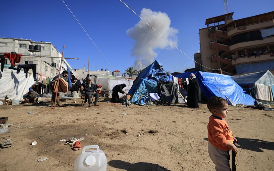 People gather near tents used as temporary shelter, as smoke rises during an Israeli strike on Khan Yunis in the southern Gaza Strip on Jan. 4, 2024, amid ongoing battles between Israel and Hamas militants.  